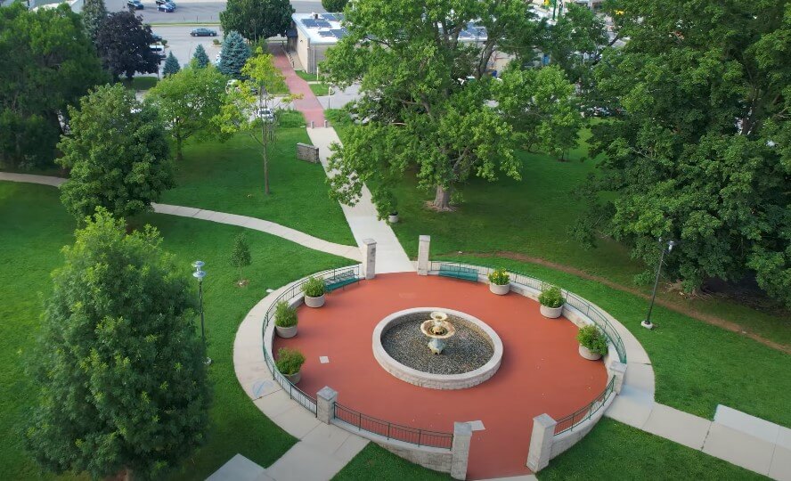 A tranquil urban oasis, featuring a central fountain surrounded by manicured lawns and pathways