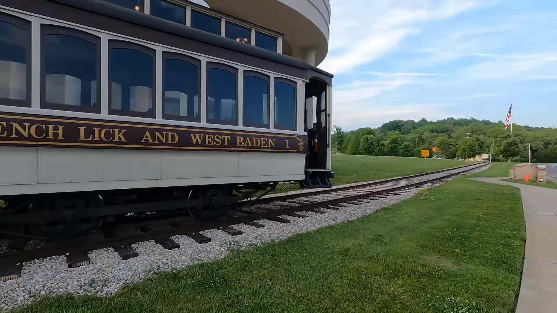 Historic railway car labeled “French Lick and West Baden” traveling along tracks beside a grassy landscape