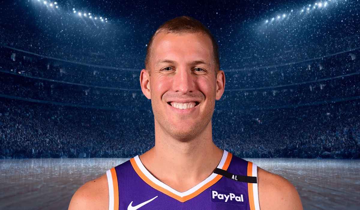 Basketball player in a purple jersey smiling on the court
