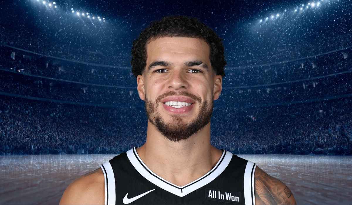 Basketball player smiling in a dark stadium filled with fans