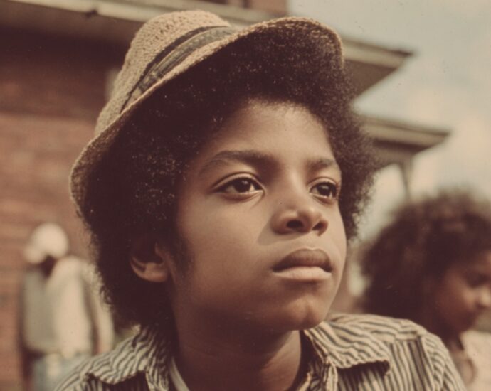 Portrait of a young boy outdoors in a 1960s neighborhood wearing a hat
