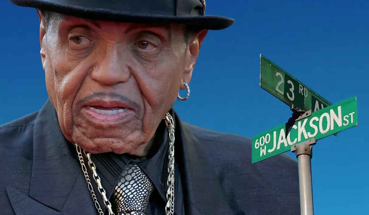 Older man wearing a hat beside a street sign reading Jackson Street