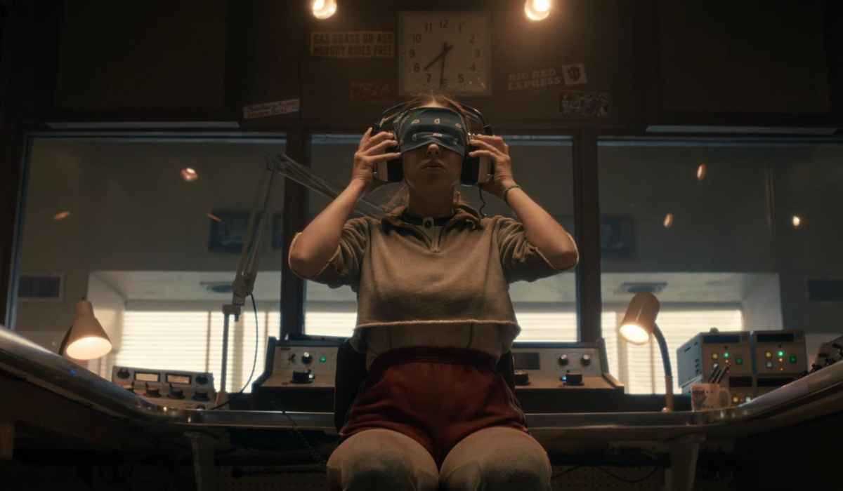 Child wearing a headset seated in a dimly lit laboratory control room