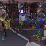 A festive holiday display under a large structure features glowing trees