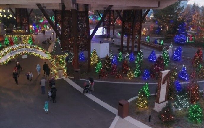A festive holiday display under a large structure features glowing trees