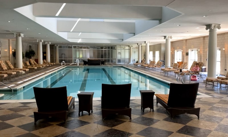 Spacious indoor pool area with checkered tile flooring, surrounded by wicker loungers