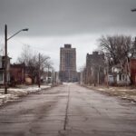 Empty residential street in Gary Indiana with older houses and a tall building in the distance