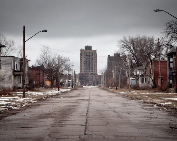 Empty residential street in Gary Indiana with older houses and a tall building in the distance
