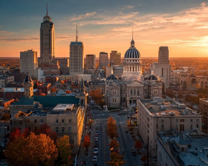 Aerial view of Indianapolis skyline at sunset with historic buildings and autumn trees