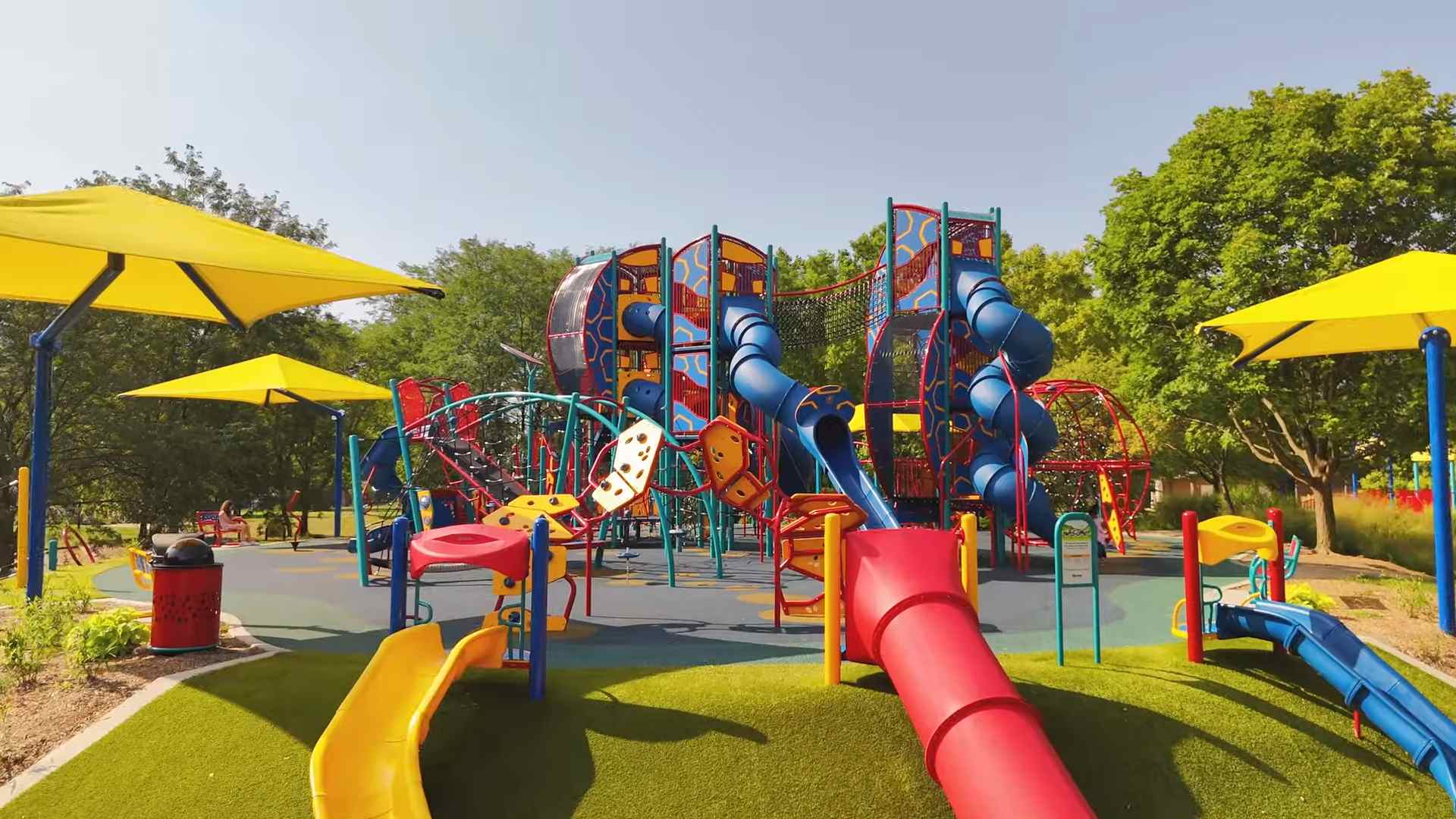 Bright playground with slides climbing structures and shade canopies in a park