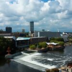 Cityscape of South Bend Indiana showing buildings, river, dam, and bridges under a partly cloudy sky