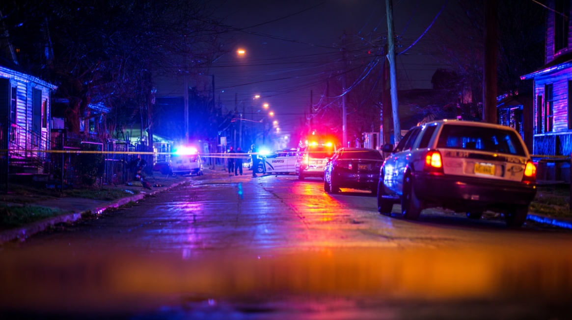 Police vehicles with flashing lights blocking a residential street at night during an investigation