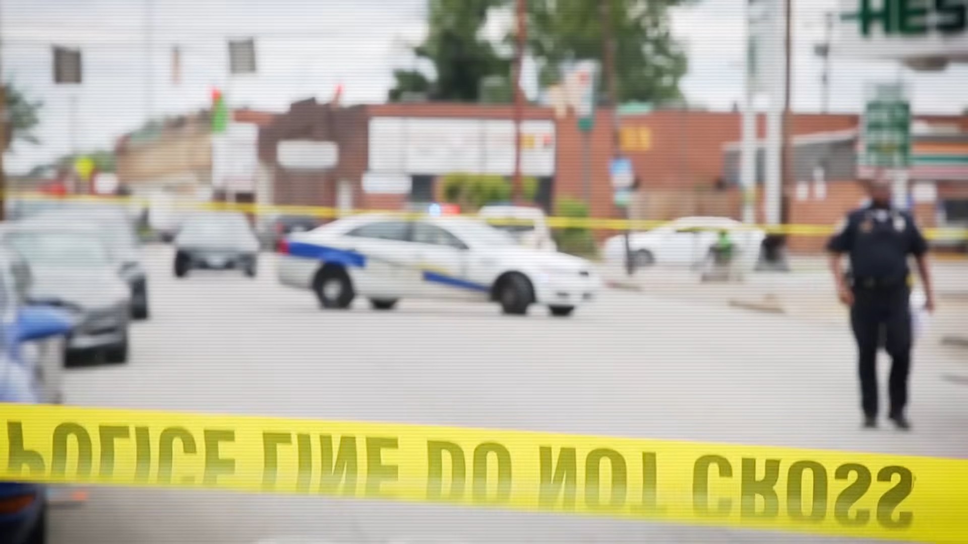 Police cars and officers near a taped off area marking a crime scene on a street