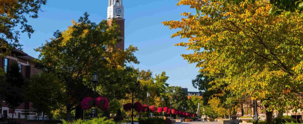 Tree lined campus path with clock tower and colorful foliage at Purdue University