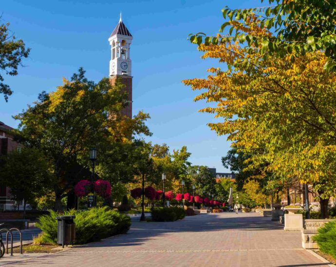 Tree lined campus path with clock tower and colorful foliage at Purdue University