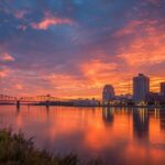 City skyline and bridge reflected on a river during a colorful sunset