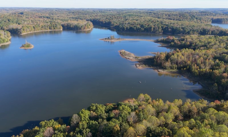Aerial view of a serene lake surrounded by dense, colorful autumn forests
