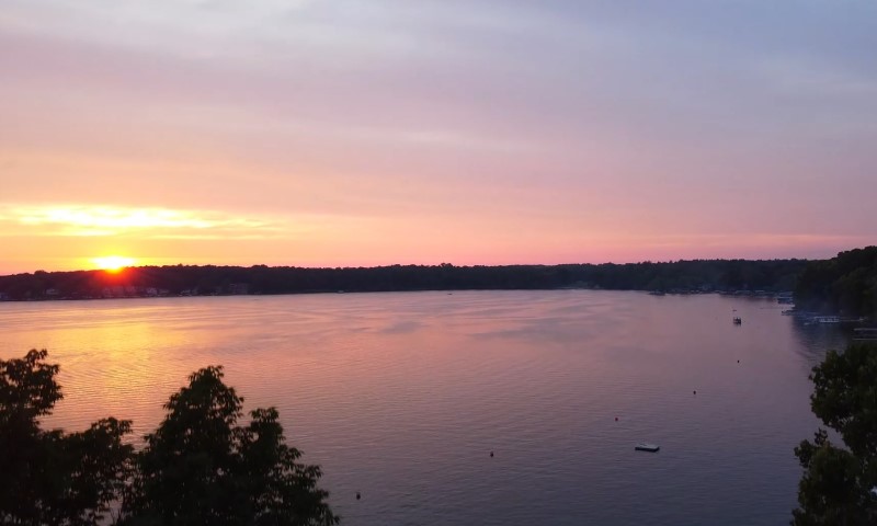 Sunset over a calm lake with a pink and orange sky reflecting on the water