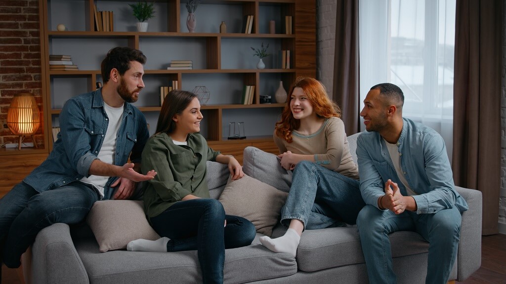 Group of people sitting on couch having conversation in a home setting