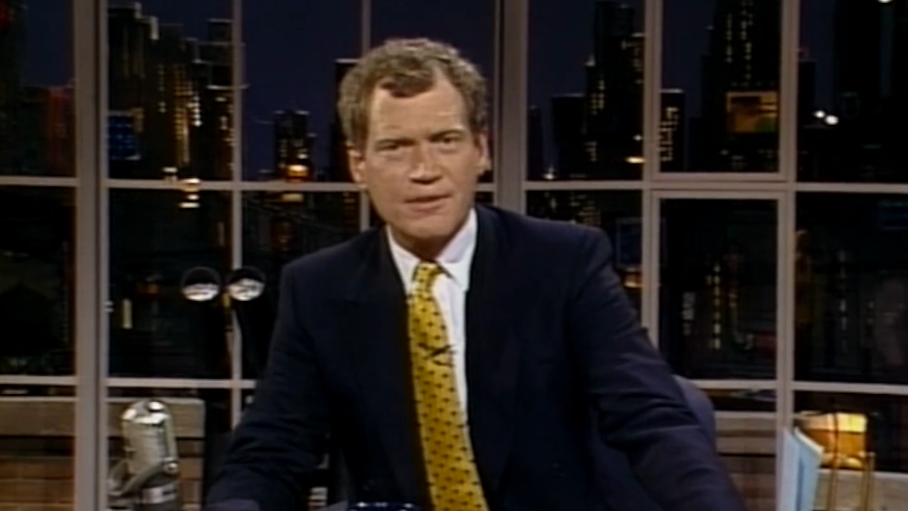 David Letterman sits behind a desk on a studio set