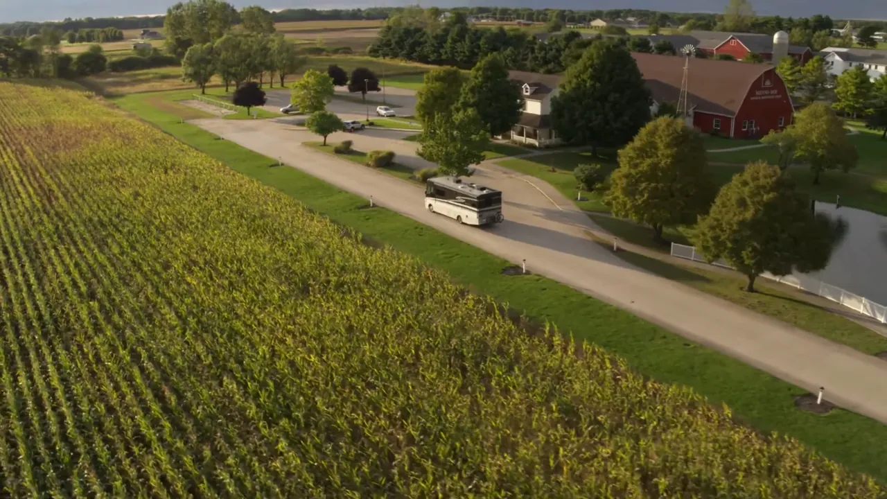 A horse-drawn buggy travels past cornfields and red barns in Shipshewana Amish Country