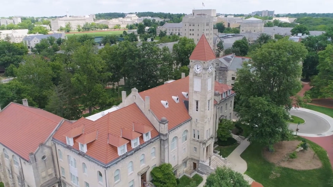 Aerial view of Indiana University with a historic clock tower and red-tiled roofs