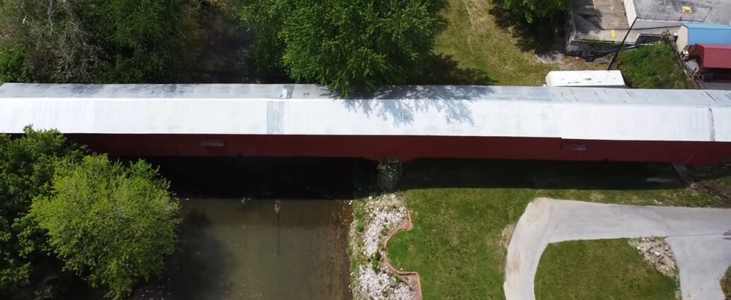 Aerial view of a red covered bridge over a creek in Parke County