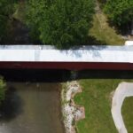 Aerial view of a red covered bridge over a creek in Parke County