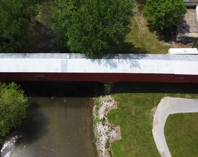 Aerial view of a red covered bridge over a creek in Parke County