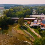 Aerial view of the Covered Bridge Festival with vendor booths, crowds, a covered bridge, and packed fields of cars