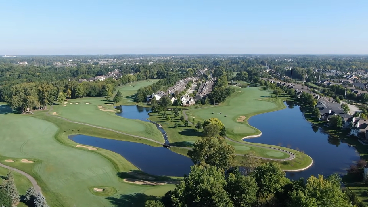 Aerial view of a Carmel golf course, lakes, homes, and tree-lined neighborhoods