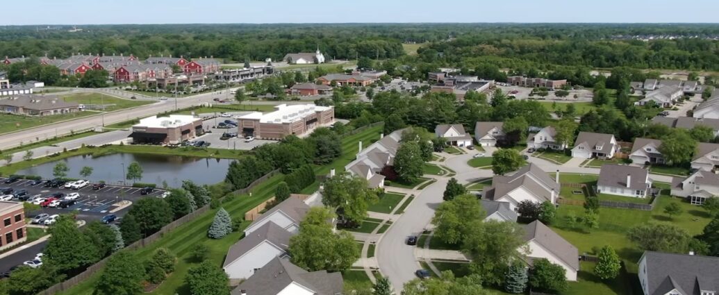 Aerial view of Carmel homes, tree-lined streets, shops, and green space