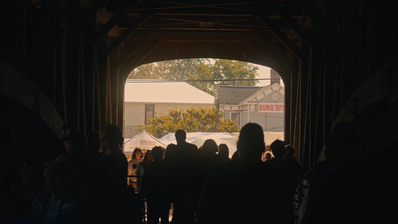 Visitors walk through a covered bridge toward craft booths at the Parke County festival