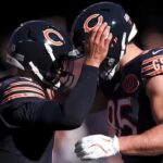 Two Chicago Bears players stand close together on the field.